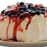 mixed berry pavlova on white cake stand