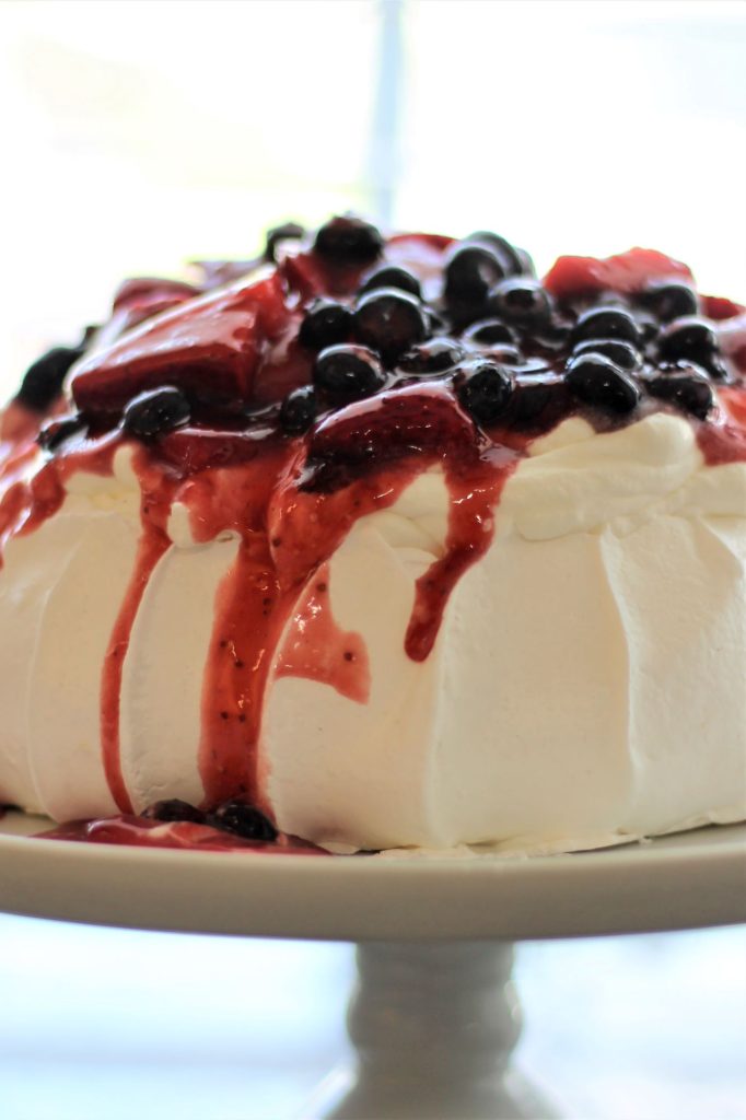 mixed berry pavlova on white cake stand