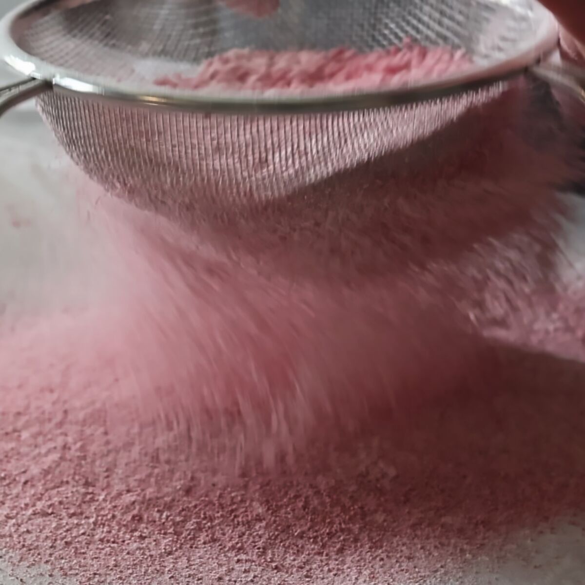 sifting strawberry powder with flour blend.