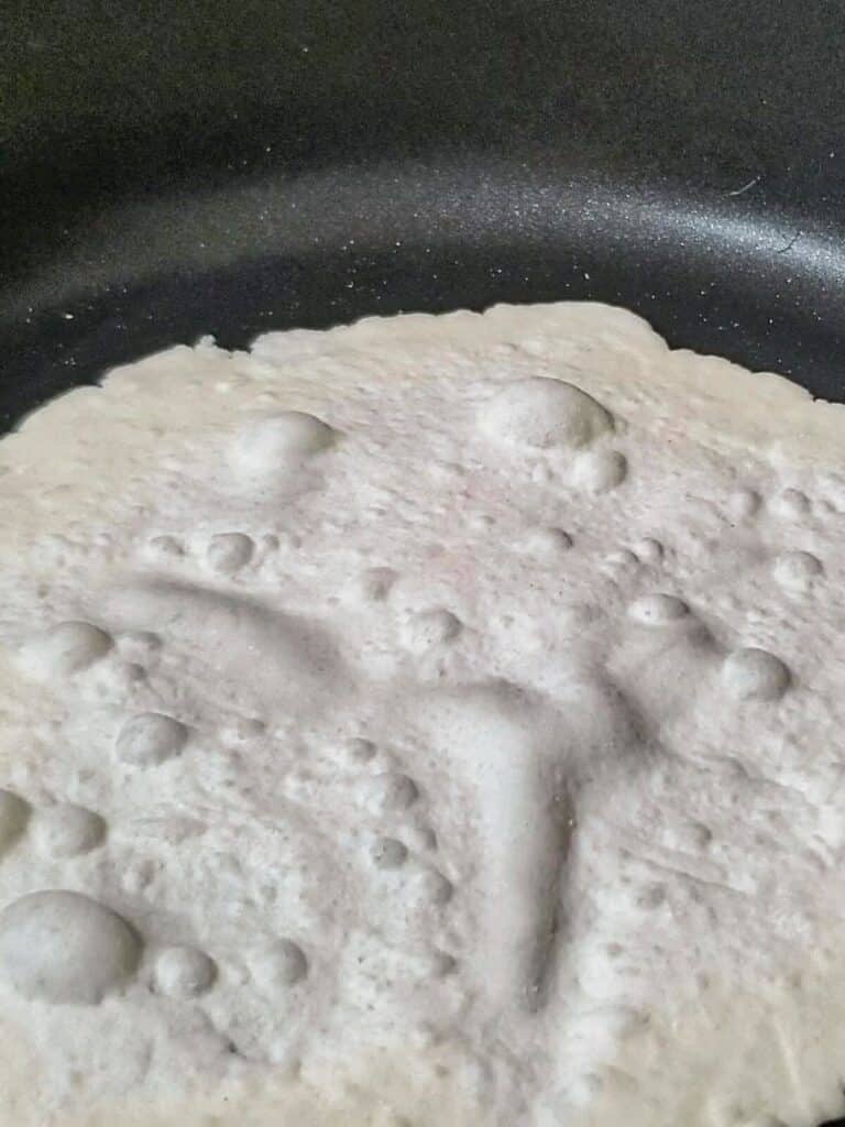 cooking tortilla on first side and seeing bubbles forming.