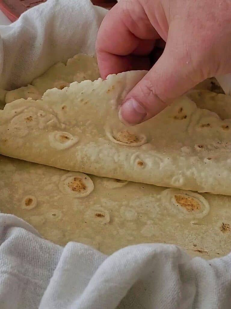 flipping tortillas over to show how pliable they are.