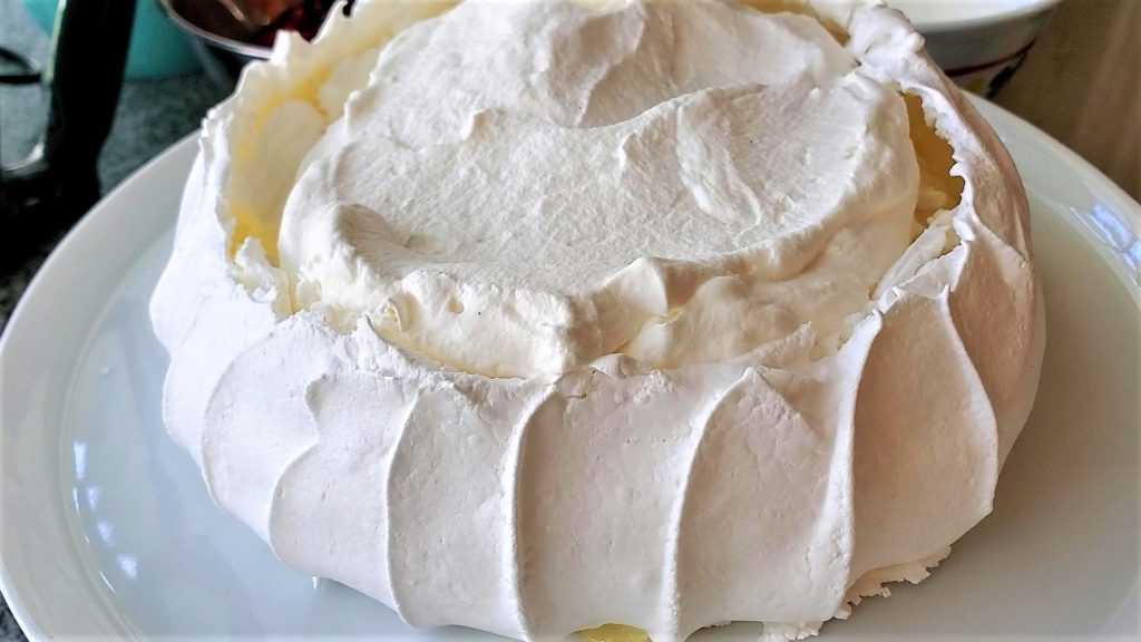 adding whipped cream to top of pavlova