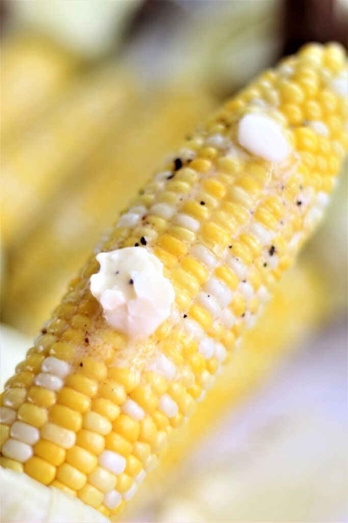 holding up an ear of corn with a small amount of butter on it