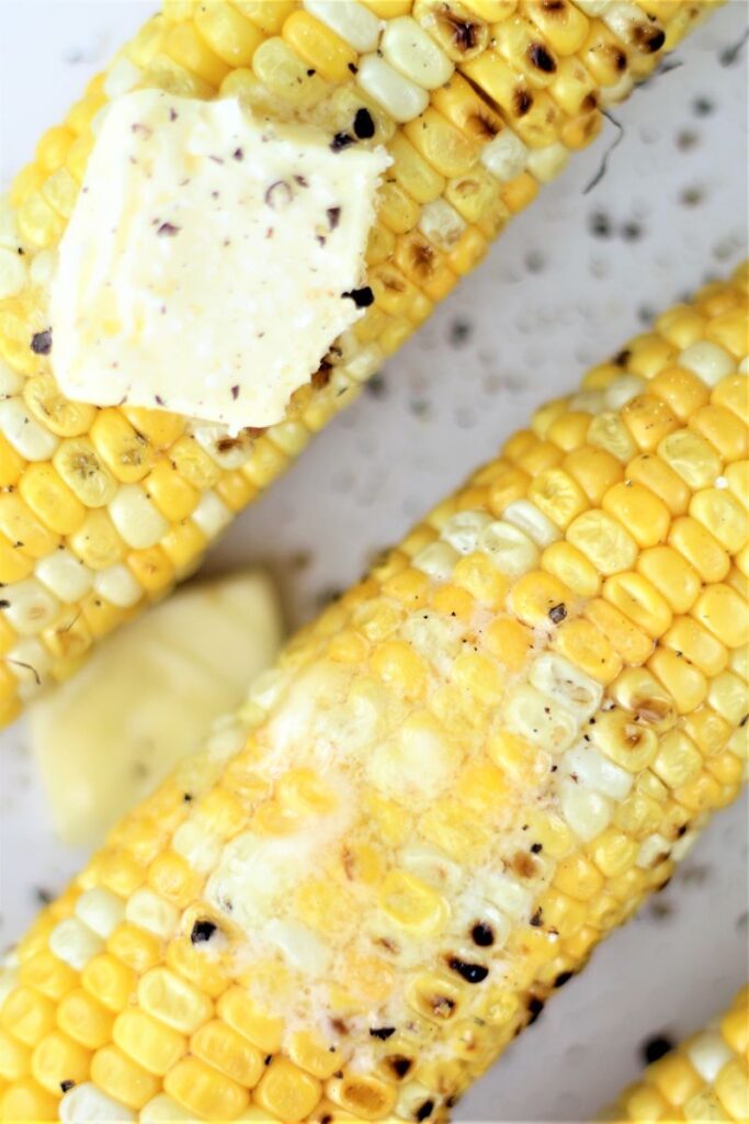 up close picture of two ears of corn with butter melted on top