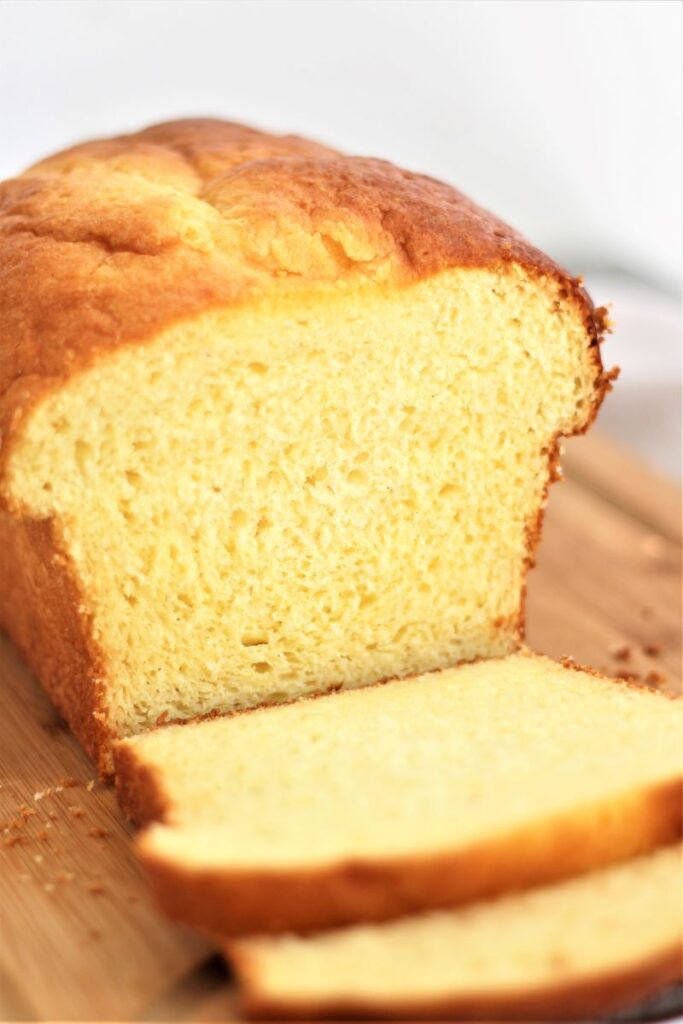 gluten free brioche loaf with a few slices cut on a wooden cutting board