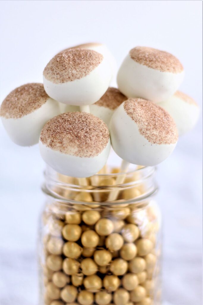 jar filled with gold round candies and gf cinnamon cake pops