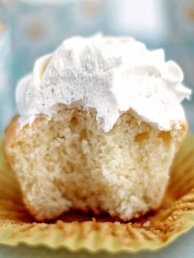 cupcake on flattened yellow cupcake liner with bite taken out of it.