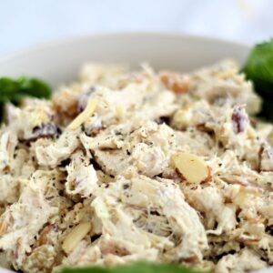 chicken salad in white bowl lined with lettuce leaves