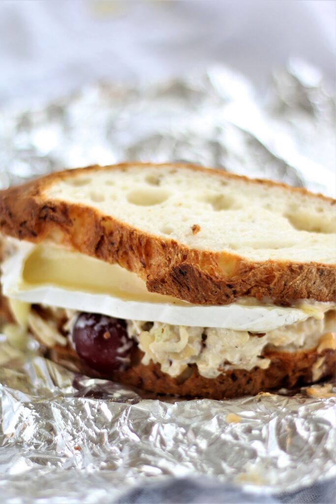 chicken salad sandwich with brie cheese on aluminum foil