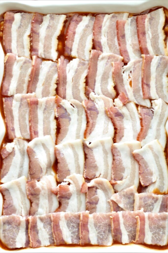 bacon pieces lined up in rows on top of baked beans