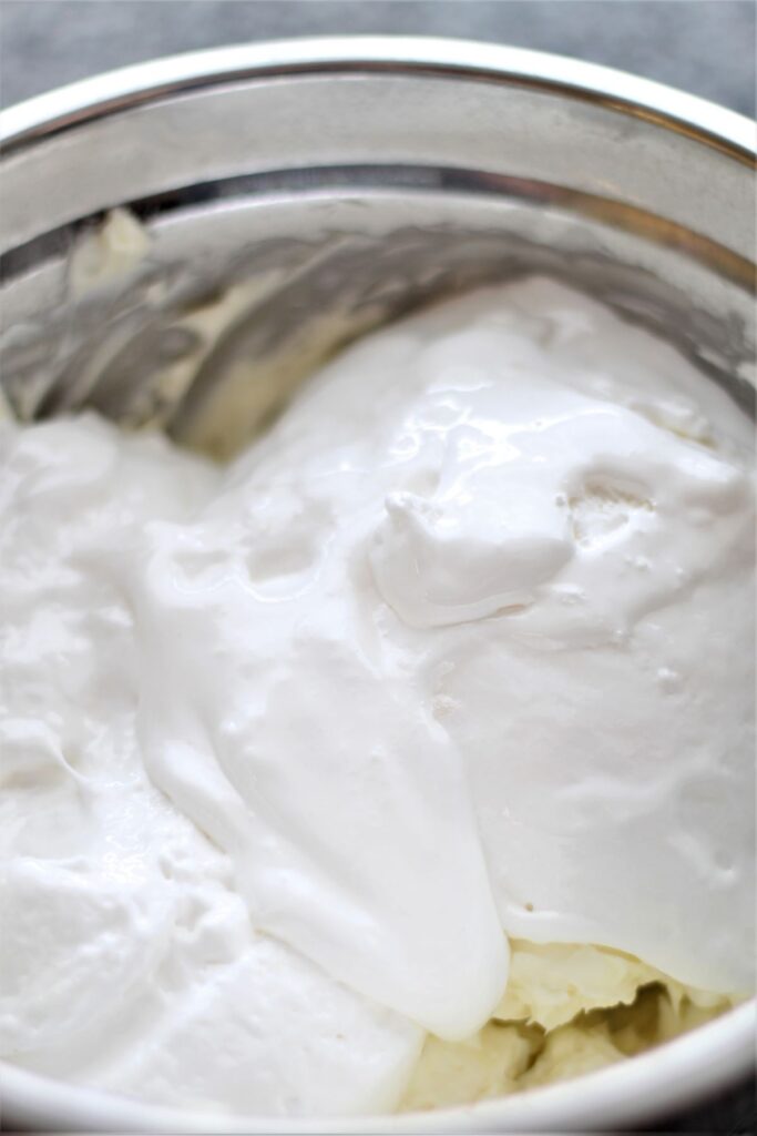 marshmallow cream on top of whipped cream cheese in stainless steel bowl