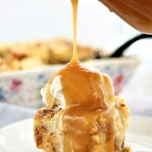 pouring butter rum sauce over bread pudding on white plate