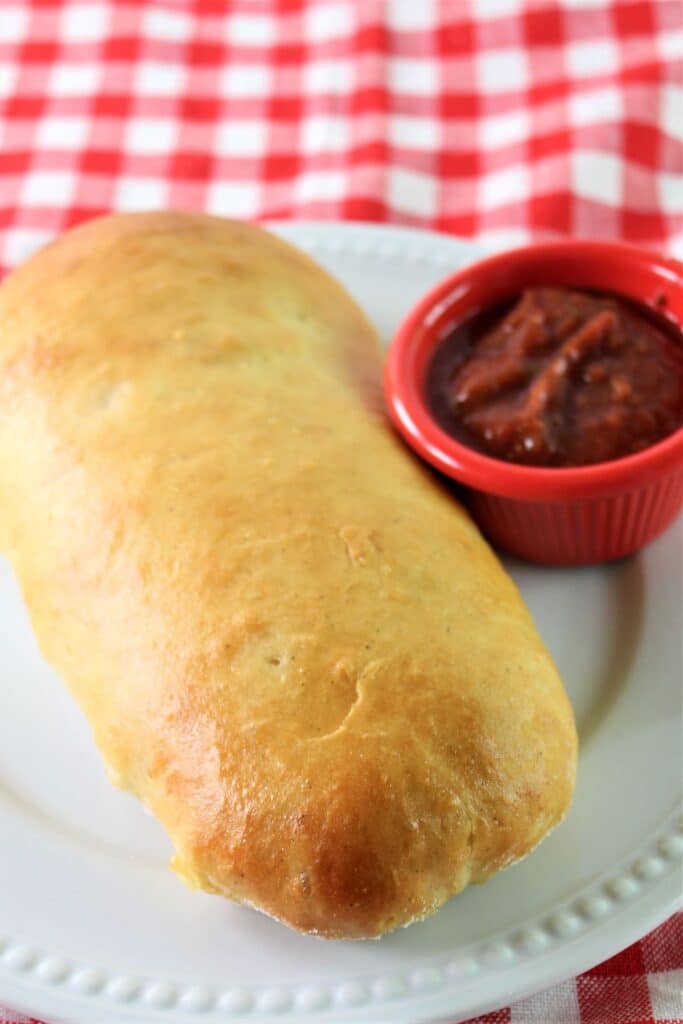 gluten free pepperoni bread on white plate with red checked napkin underneath