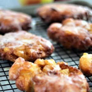 gluten free apple fritters on wire rack with apples in the background
