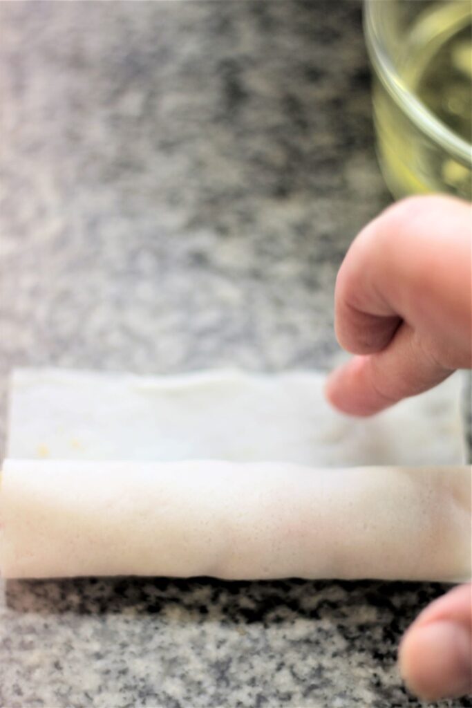 sealing edge of lumpia with finger dipped in water