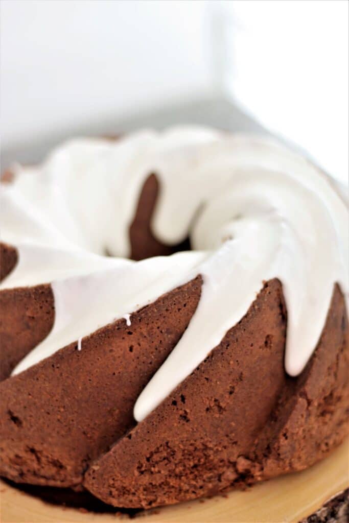 whole apple bundt cake with dripping white icing on live edge wood plate