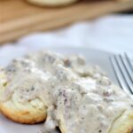 sausage gravy over biscuits on white plate