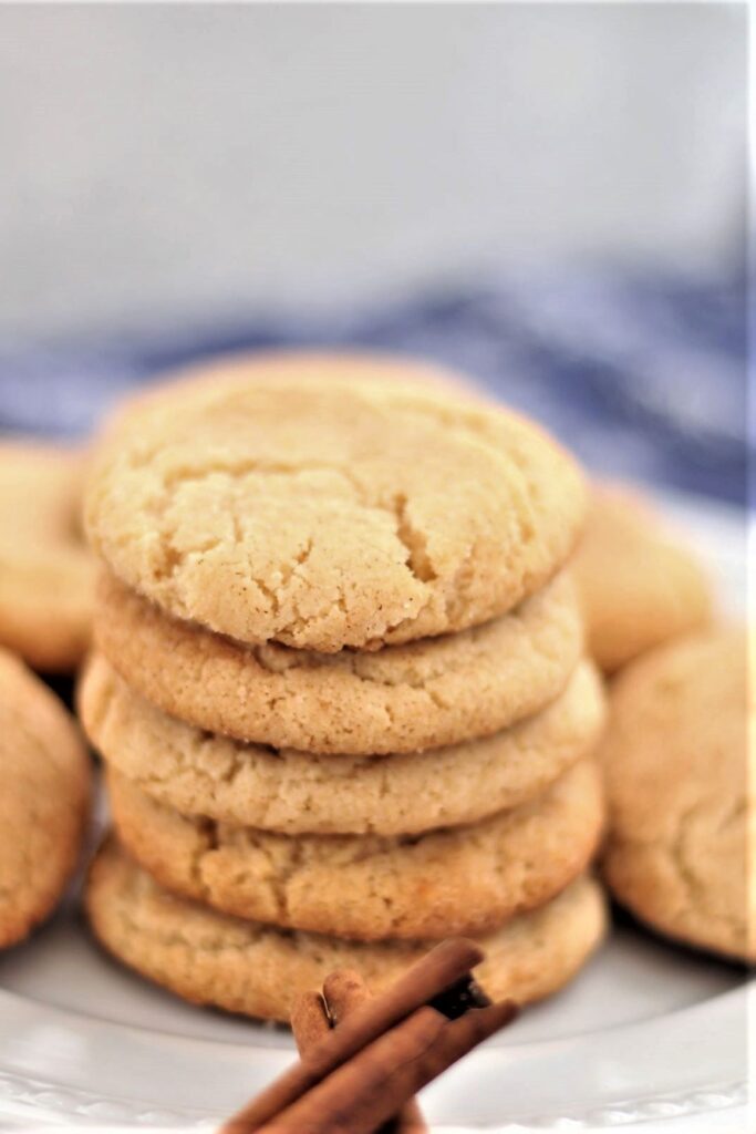 gluten free snickerdoodles stacked on a white plate over a blue napkin