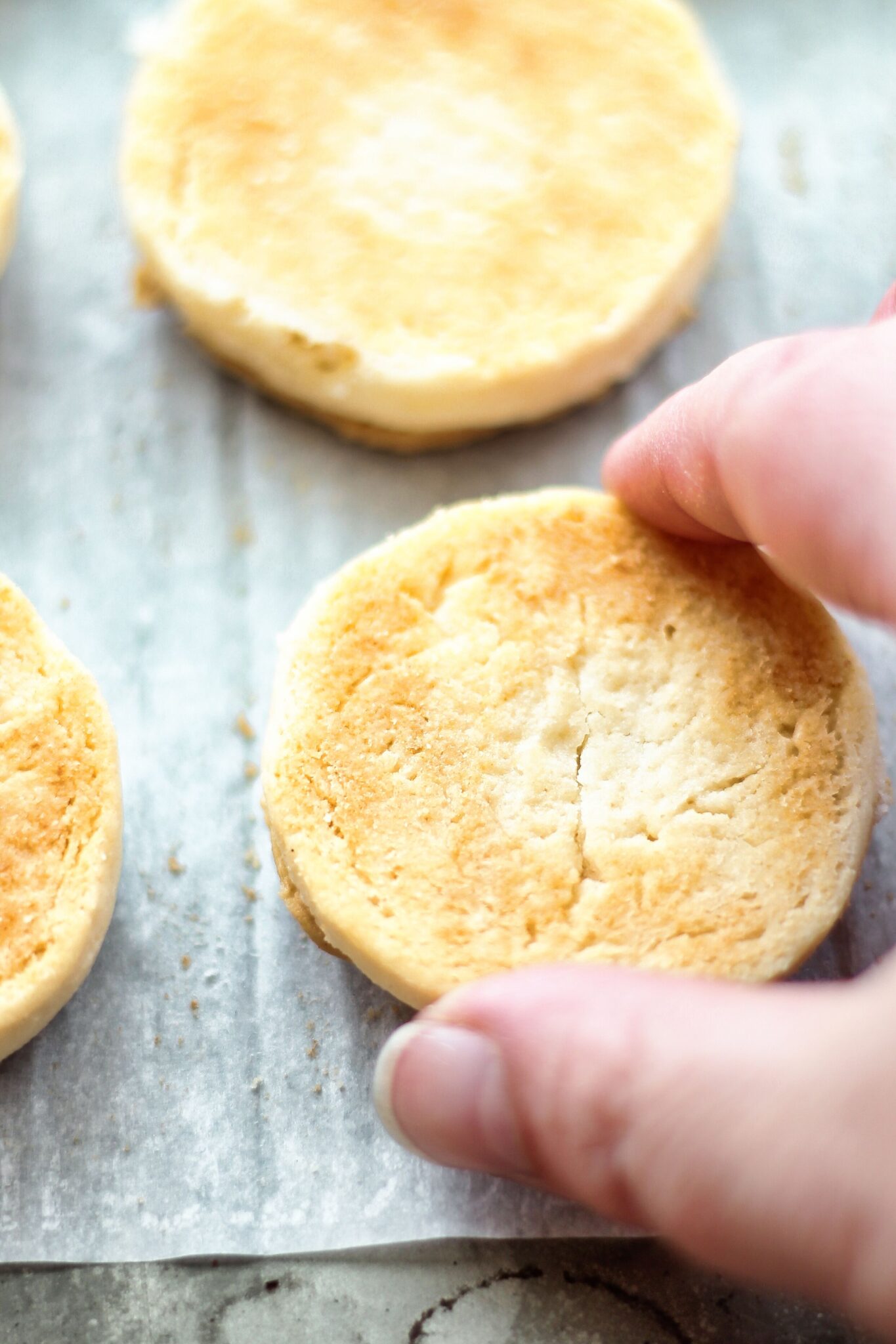 flipping cookies over onto parchment to flatten top of filling