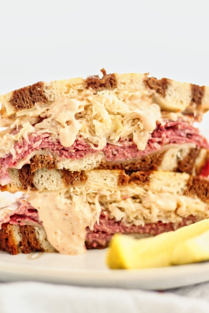 reuben sandwich on marble rye with pickle spears on white plate