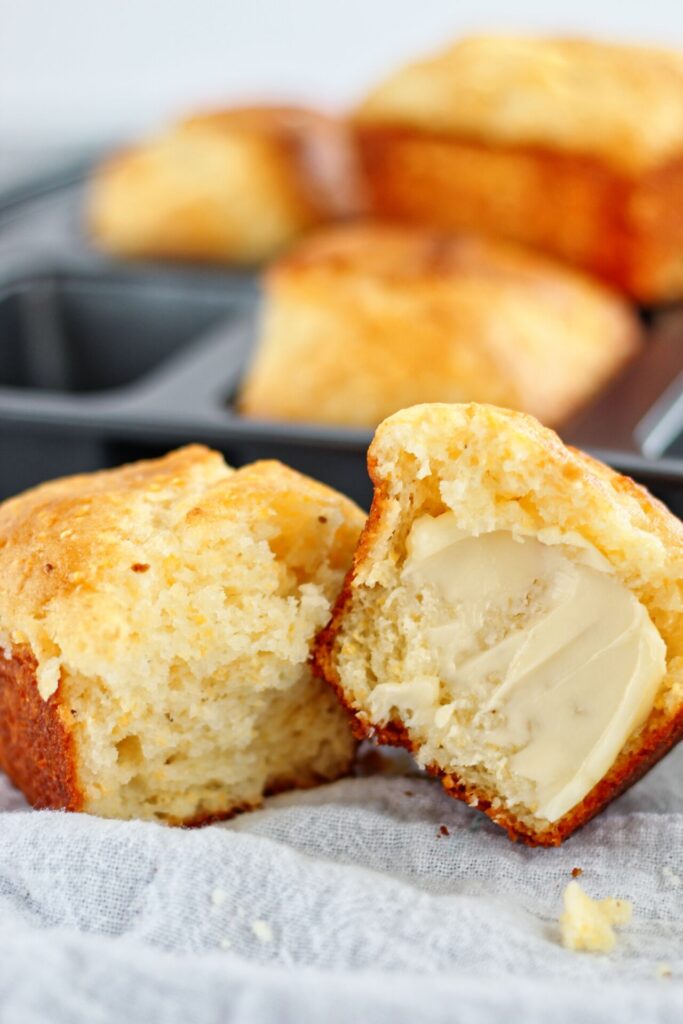 split in half gluten free sweet cornbread with butter on one half and mini loaves in the background