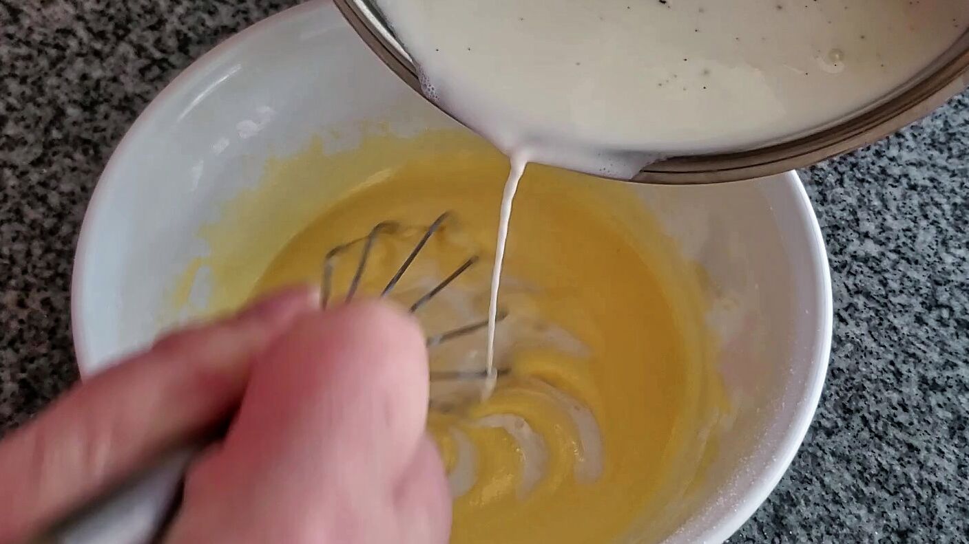 adding hot milks to egg yolk mixture