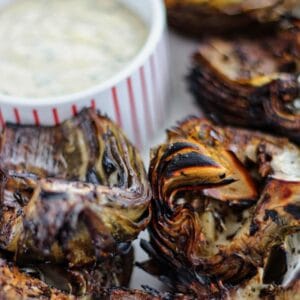 fire roasted artichokes on white platter with dipping aioli