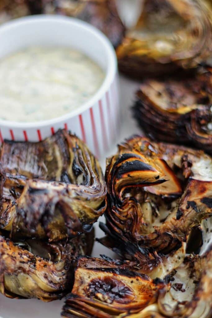 fire roasted artichokes on white platter with dipping aioli