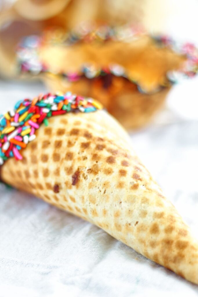 waffle cone and bowl dipped in chocolate and colored sprinkles