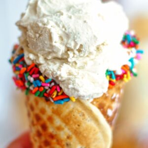 gluten free waffle cone dipped in chocolate and sprinkles and filled with vanilla ice cream