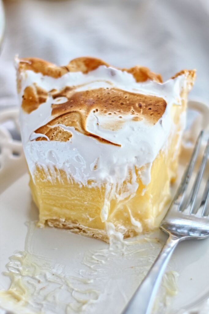 half eaten slice of lemon meringue pie on white plate