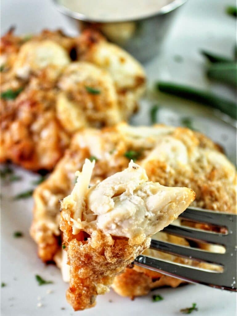 fork full of crab meat from a crab cake with green beans in the background.