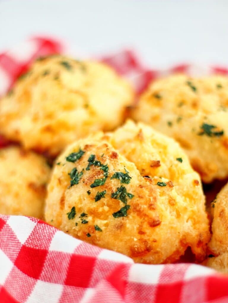 basket of gluten free cheddar bay biscuits lined with red checked napkin