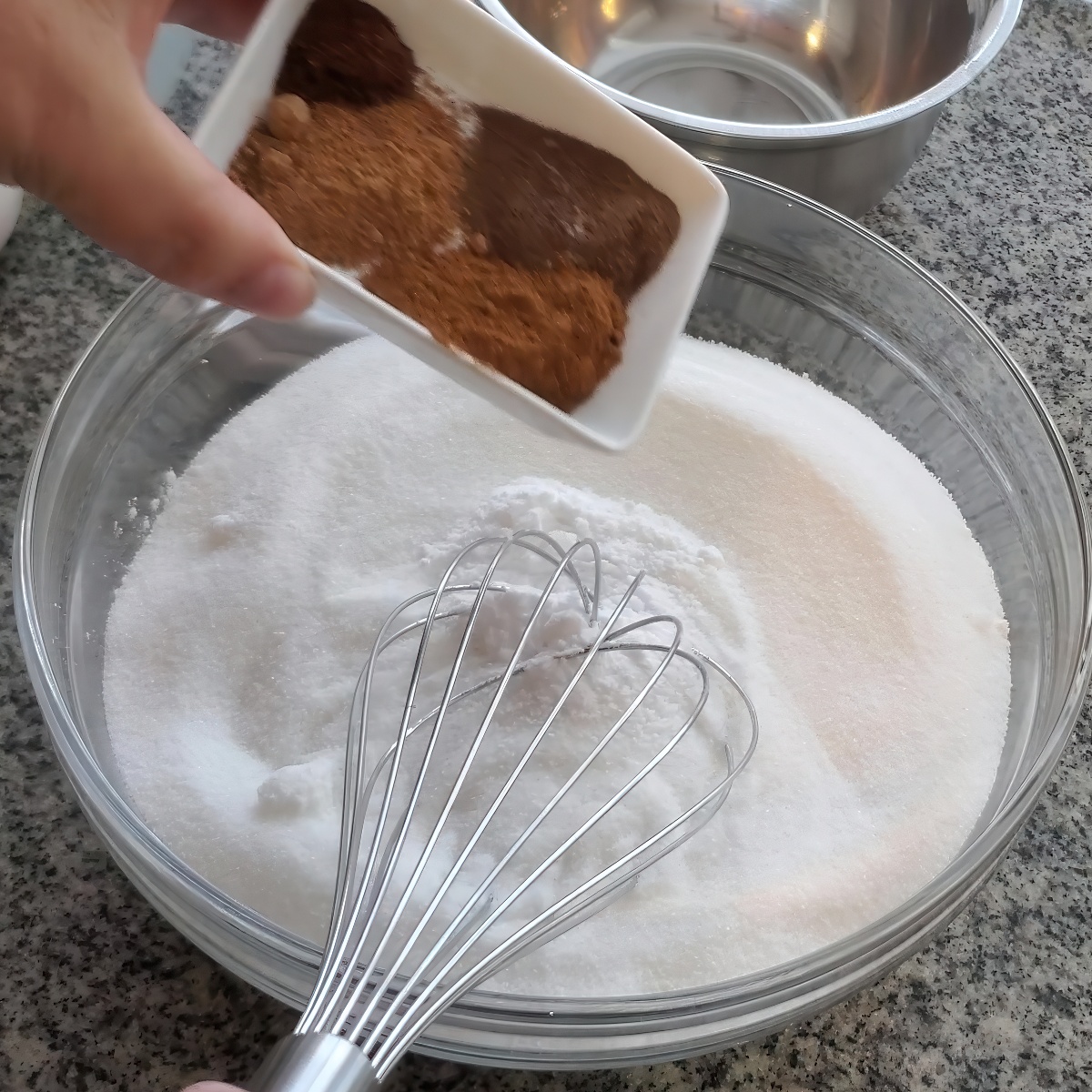 adding spices to sugar and flour in large glass bowl.