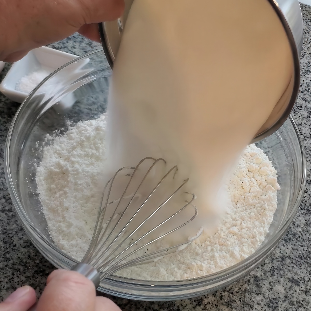 pouring sugar into flour in large glass bowl.