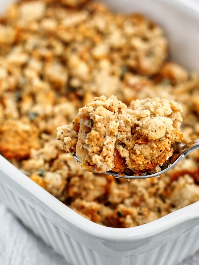 gluten free stuffing being scooped out of a white rectangular baking dish.