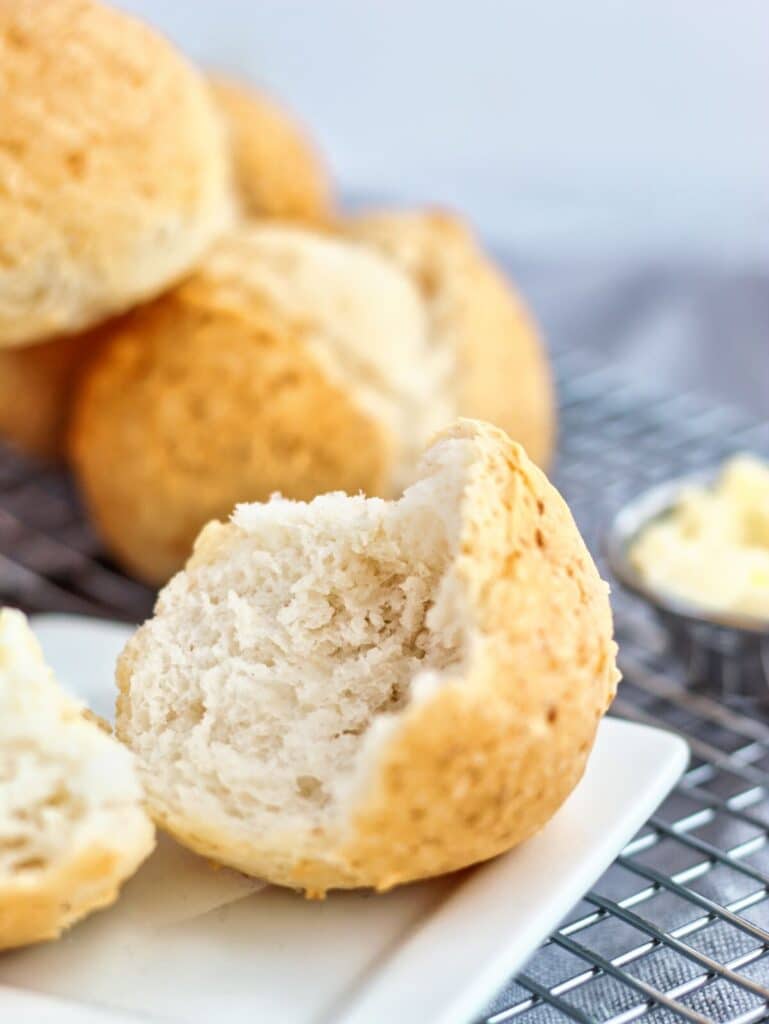 up close shot of split open roll on small white square plate with butter to the side.