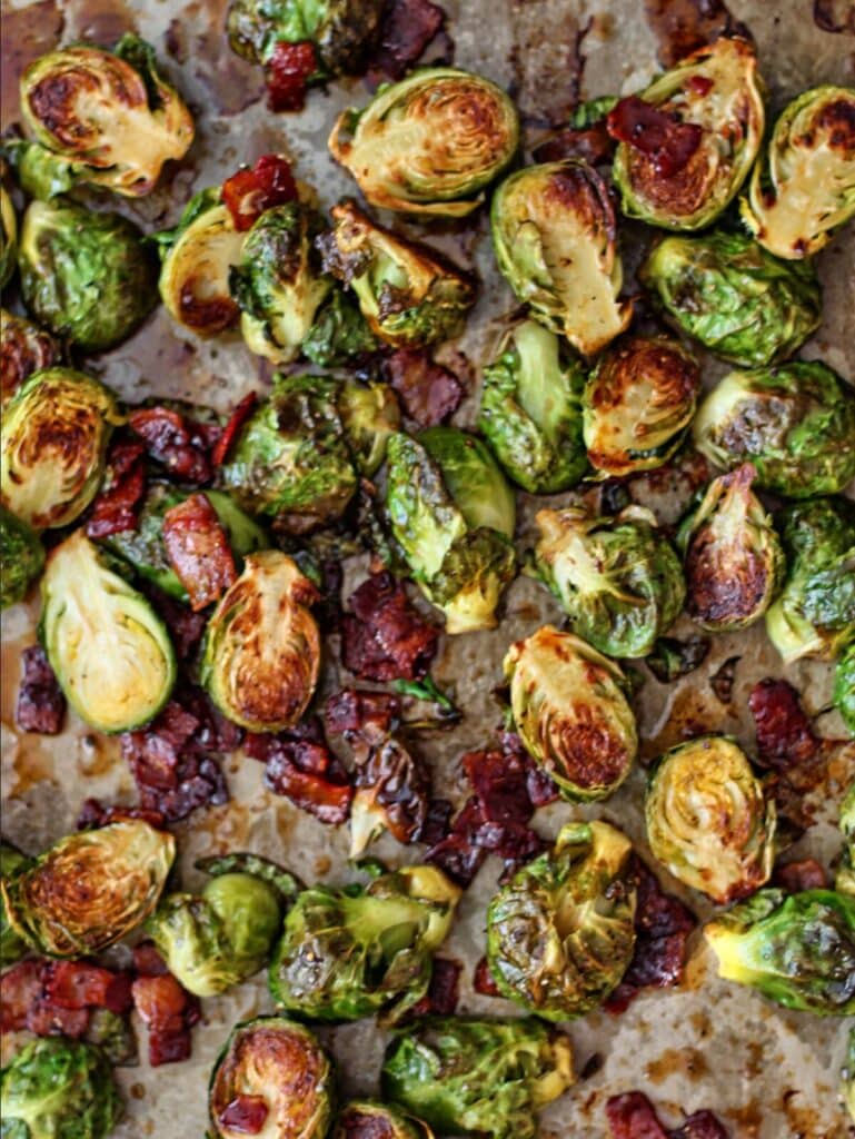 roasted brussels sprouts and bacon on baking sheet with cider glaze drizzled over.