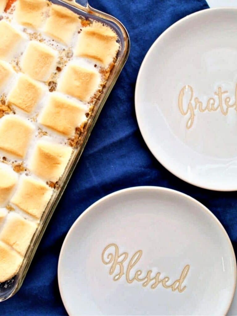 gluten free sweet potato casserole on blue napkin with grateful and blessed white and gold plates beside it.