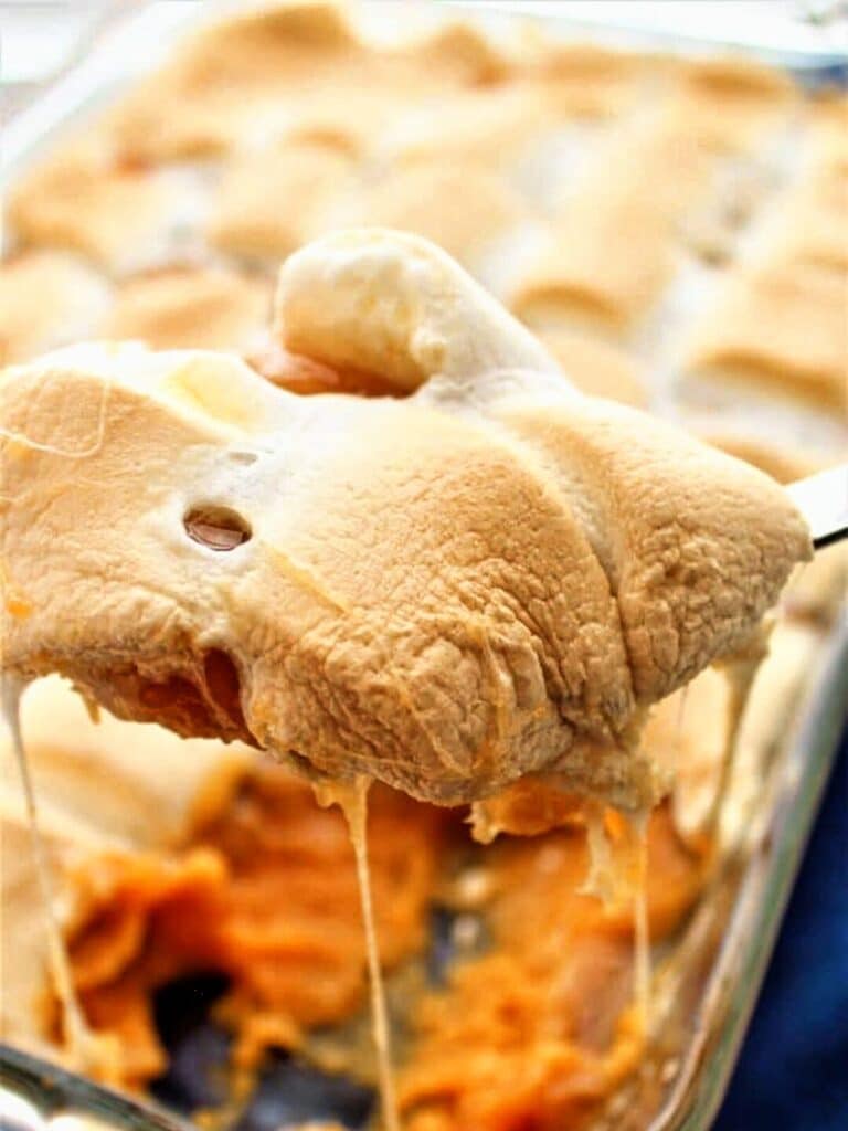 scoop of sweet potatoes on large spoon with marshmallow pulls underneath.