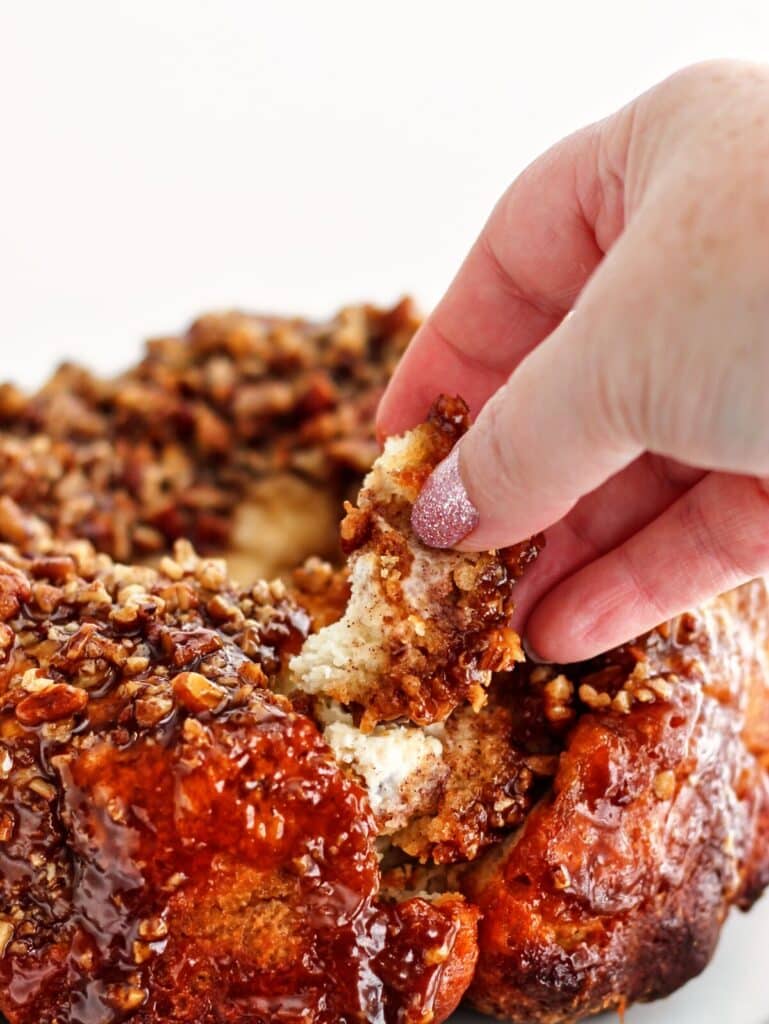 picking a piece of monkey bread from top with lots of pecans.