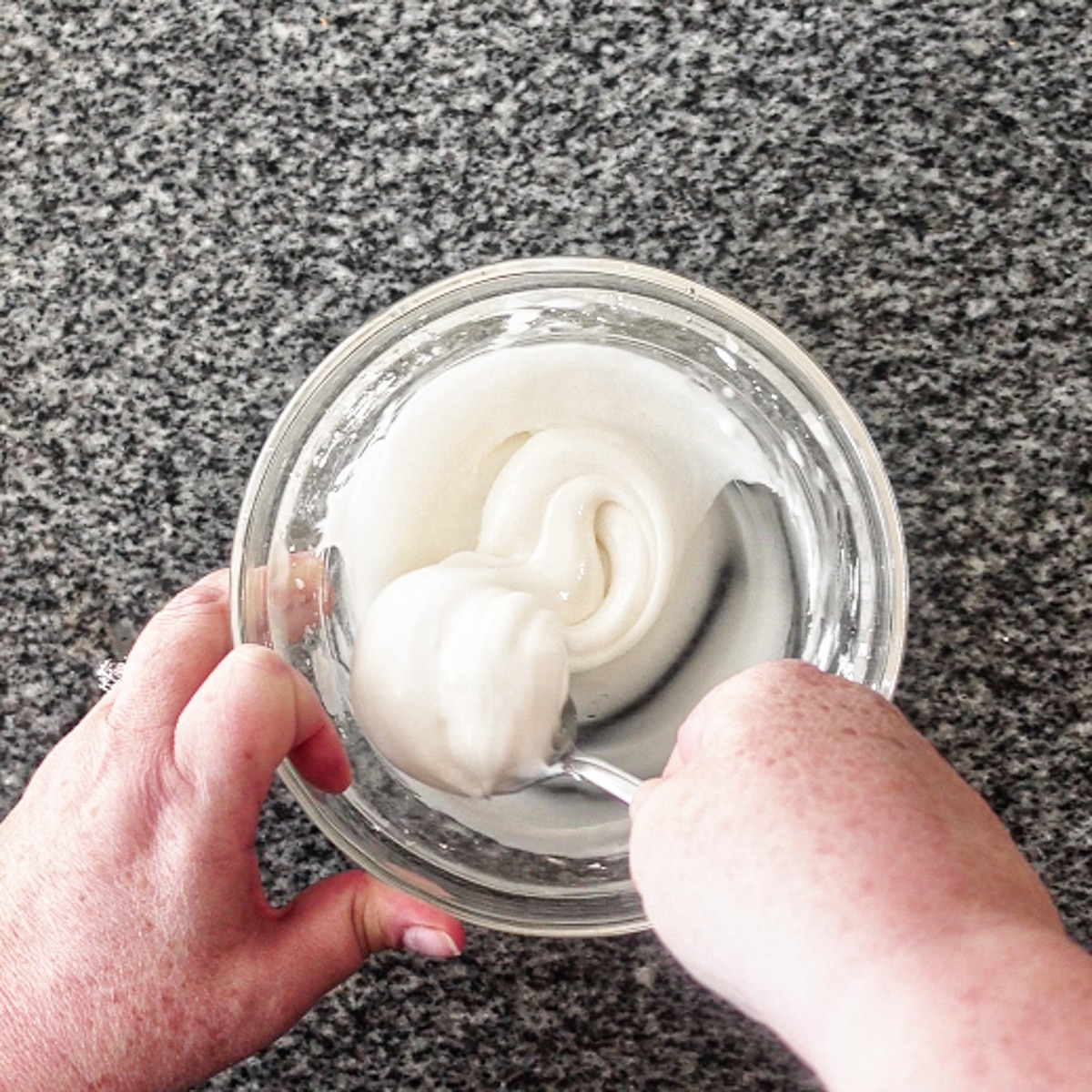 stirring icing ingredients in small glass bowl with spoon.