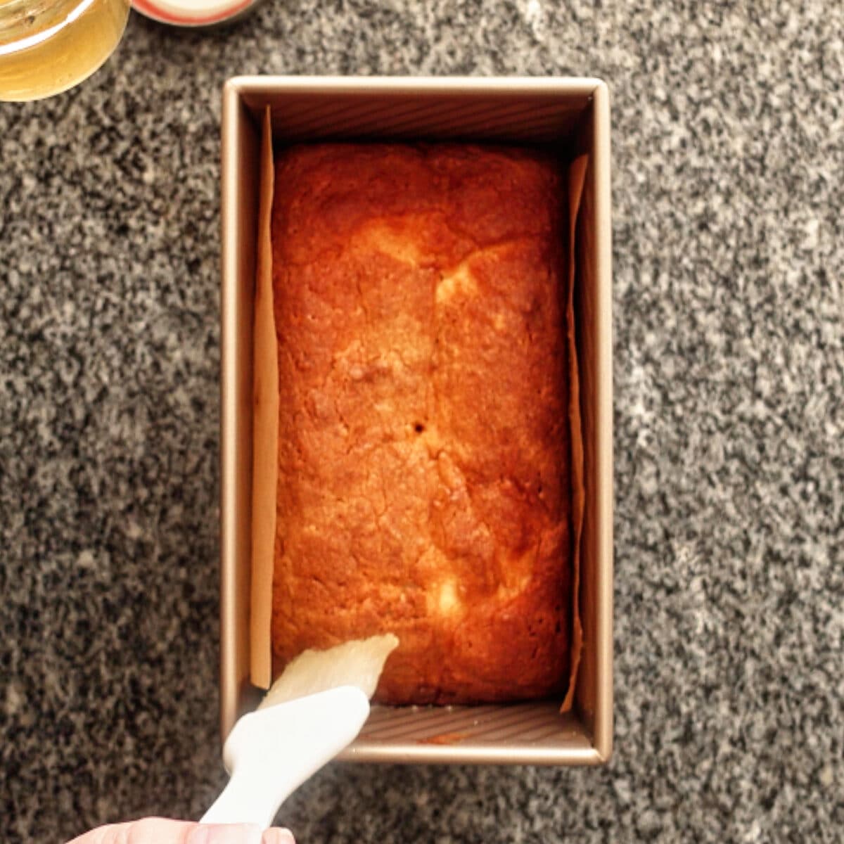 brushing lemon simple syrup over top of cake.