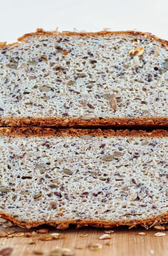 loaf of multigrain seeded bread cut in half and each half stacked on top of each other.