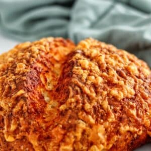 loaf of gluten free potato cheddar bread on white counter with green towel in the background.