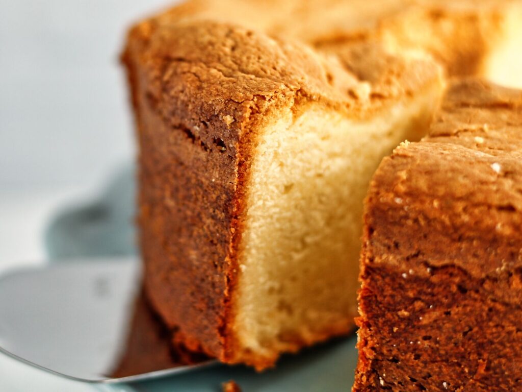 serving slice of pound cake from whole cake on baby blue cake stand.