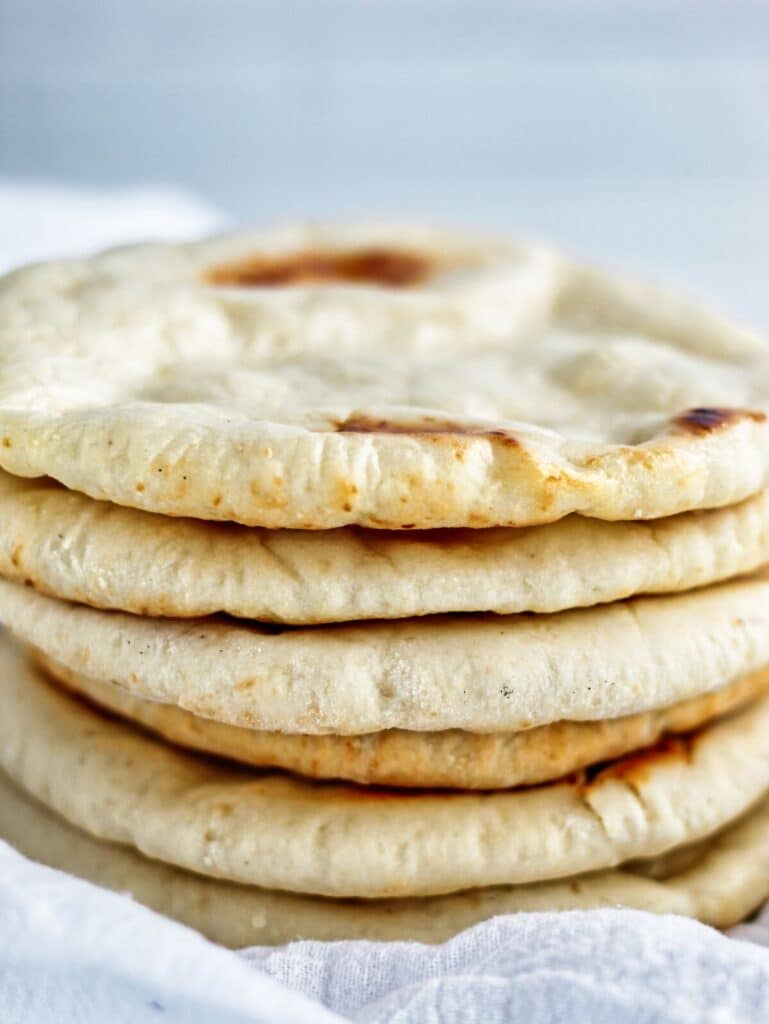 stack of several pita bread on white towel.