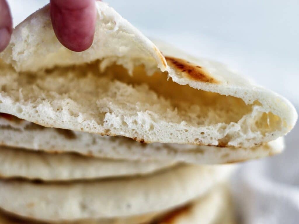 showing inside of cut open pita pocket on top of stack of pitas.