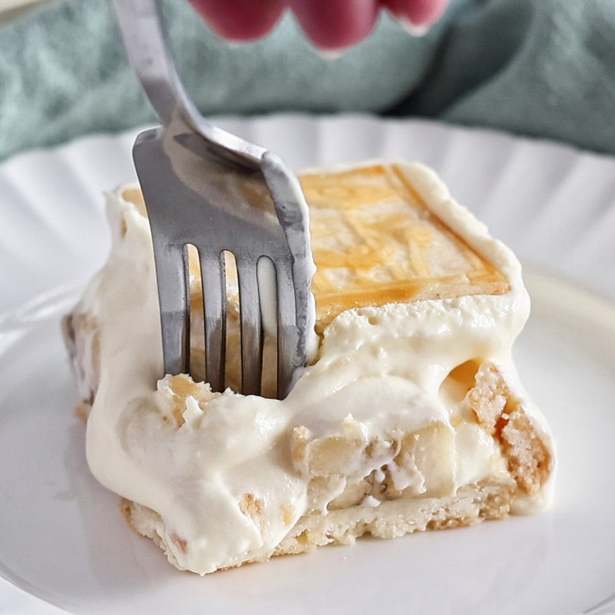 sinking fork into slice of banana pudding on white plate.