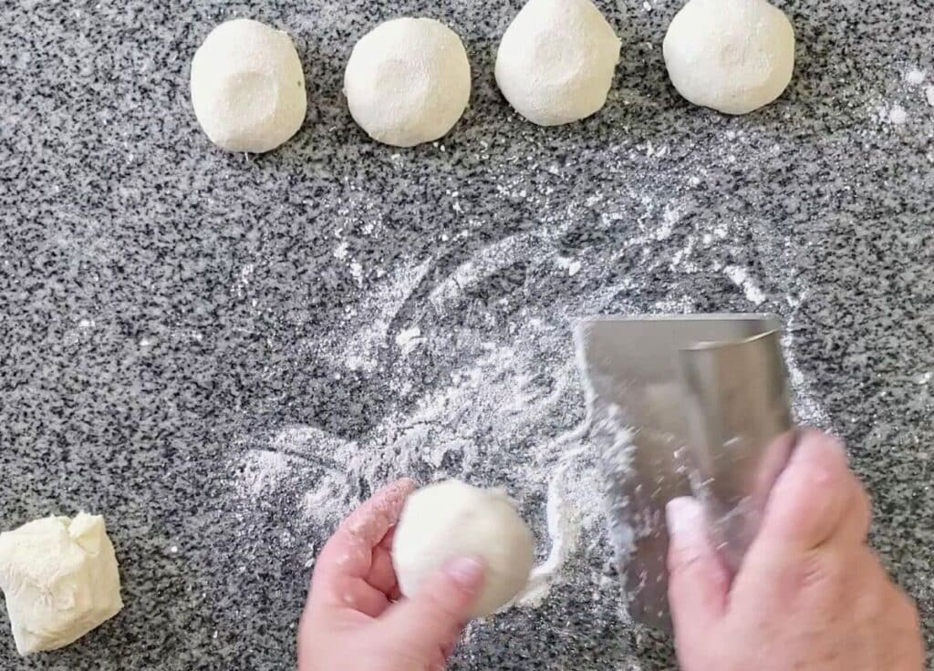 rolling divided dough into smooth round dough balls.